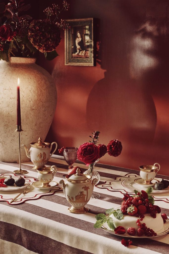 Festive table with a red and white striped tablecoth, scalloped napkins and a red tapered candle.