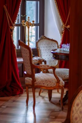 Castle living room with red velvet curtains, gilded chairs and a chess set