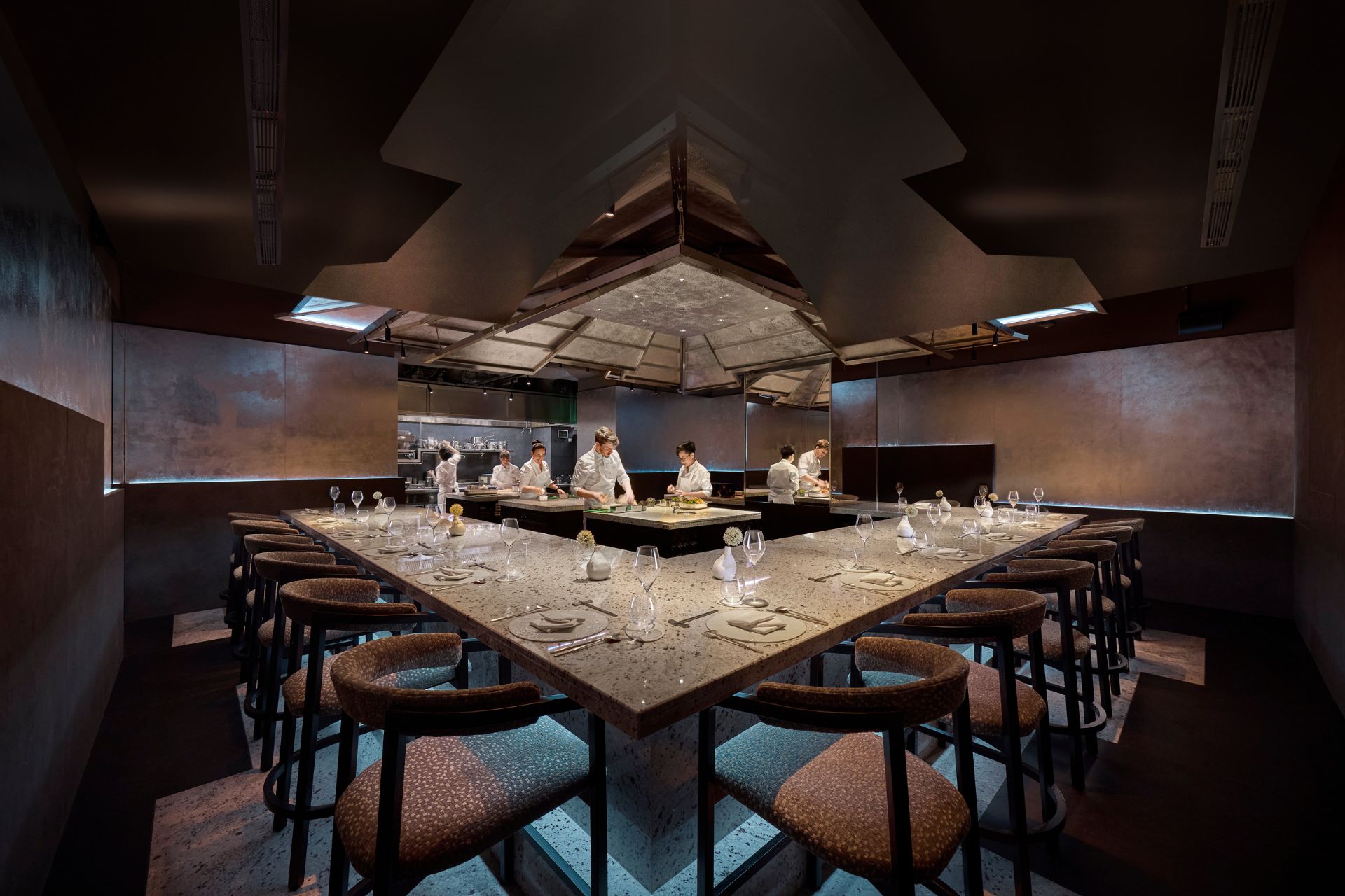 Stone counter with chefs preparing food in the middle