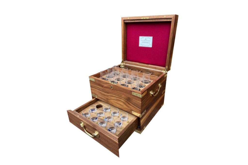Wooden shotbox containing crystal glassware, with a red felt lid.