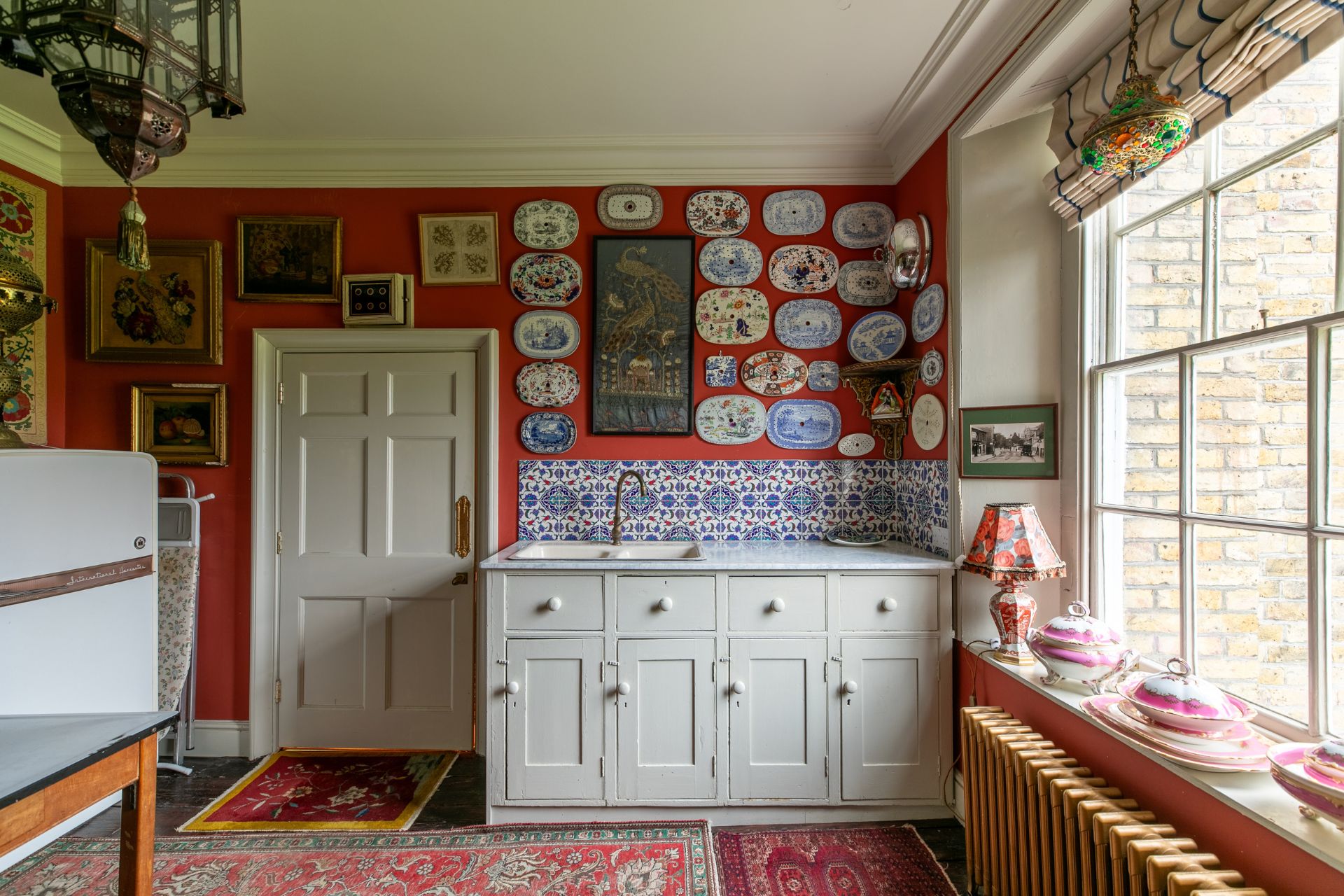 Farmhouse-style kitchen with red walls and a Persian rug