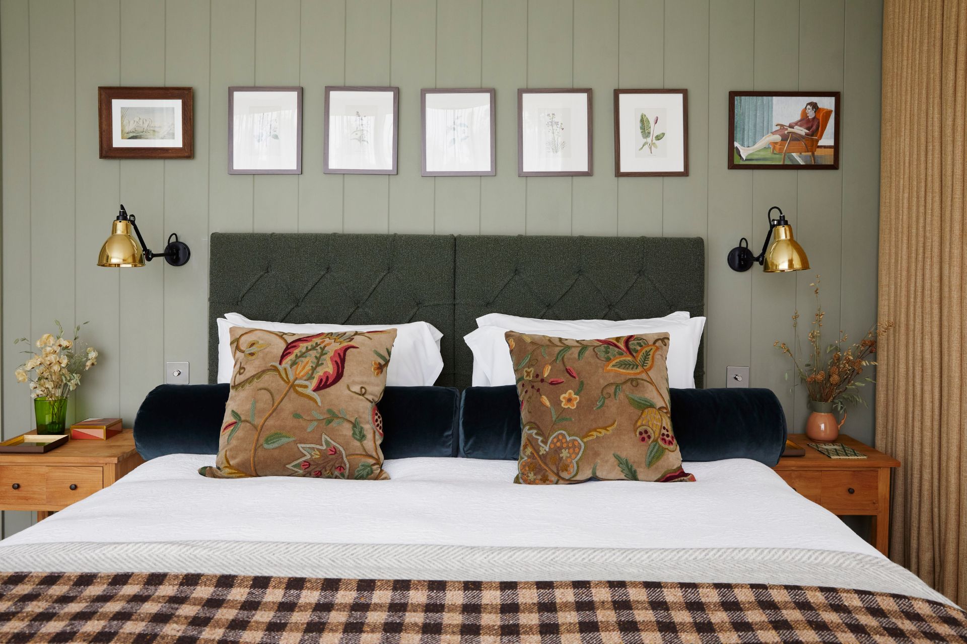 Bedroom with sage green paneled walls and an orange and black gingham bedspread