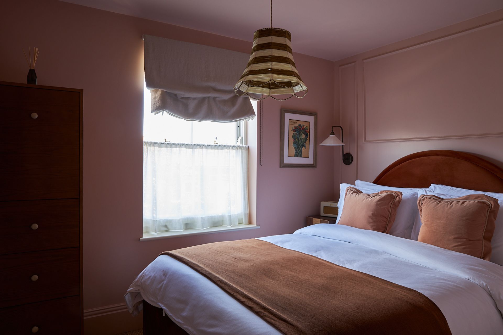 Dusty pink bedroom with crescent shaped burgundy headboard