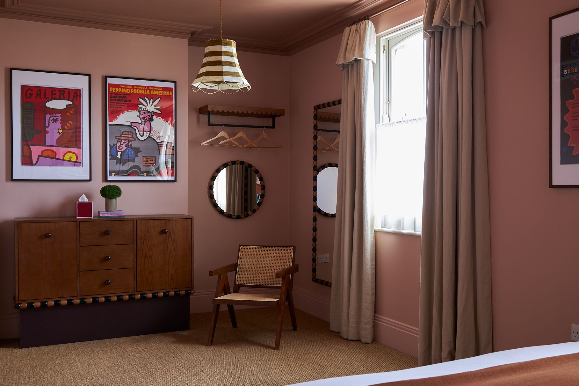 Dusty pink room with dark wooden dresser and red and white striped lampshade