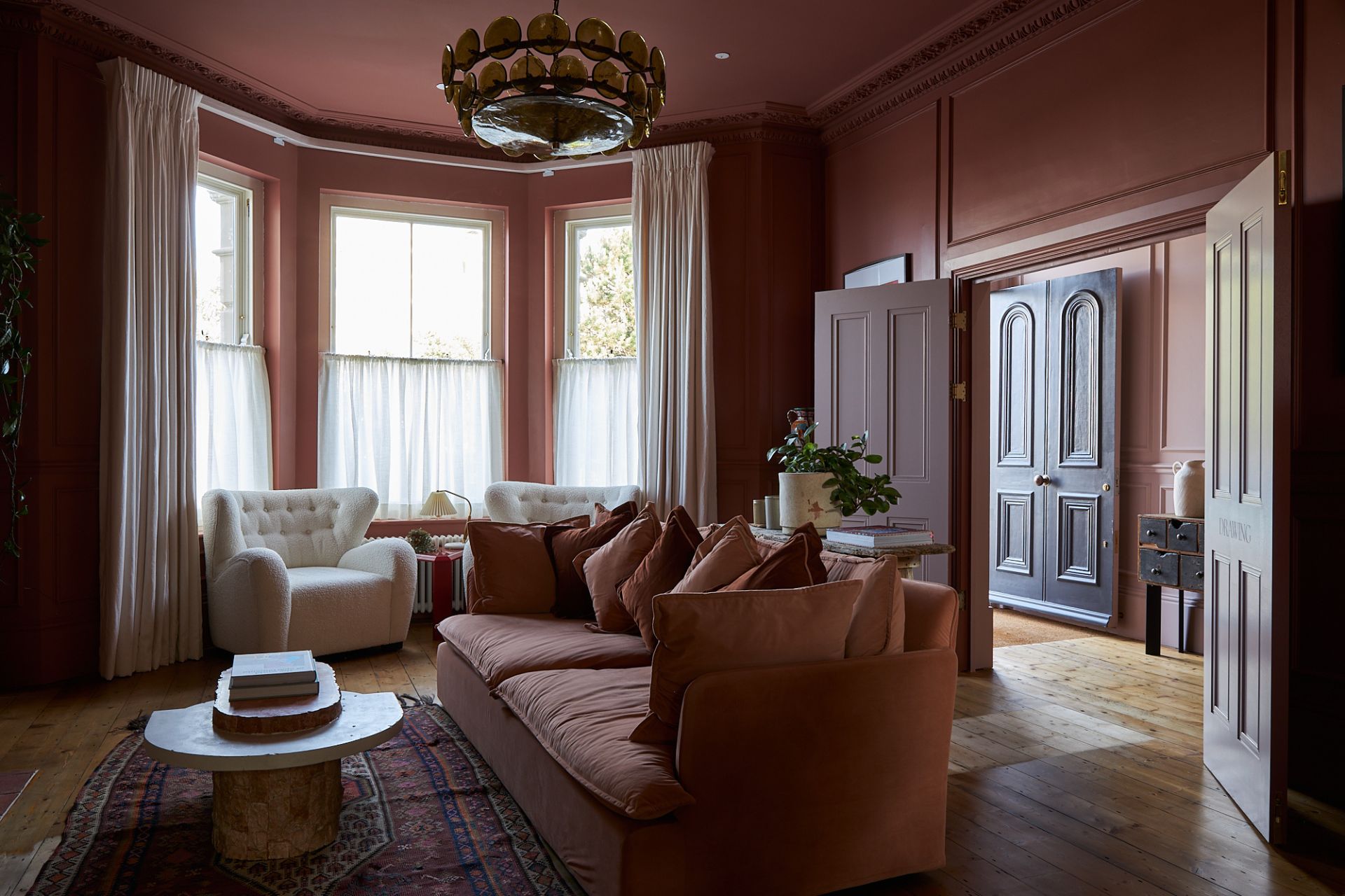 Dusty pink lounge with bay windows, pink sofas and white armchairs