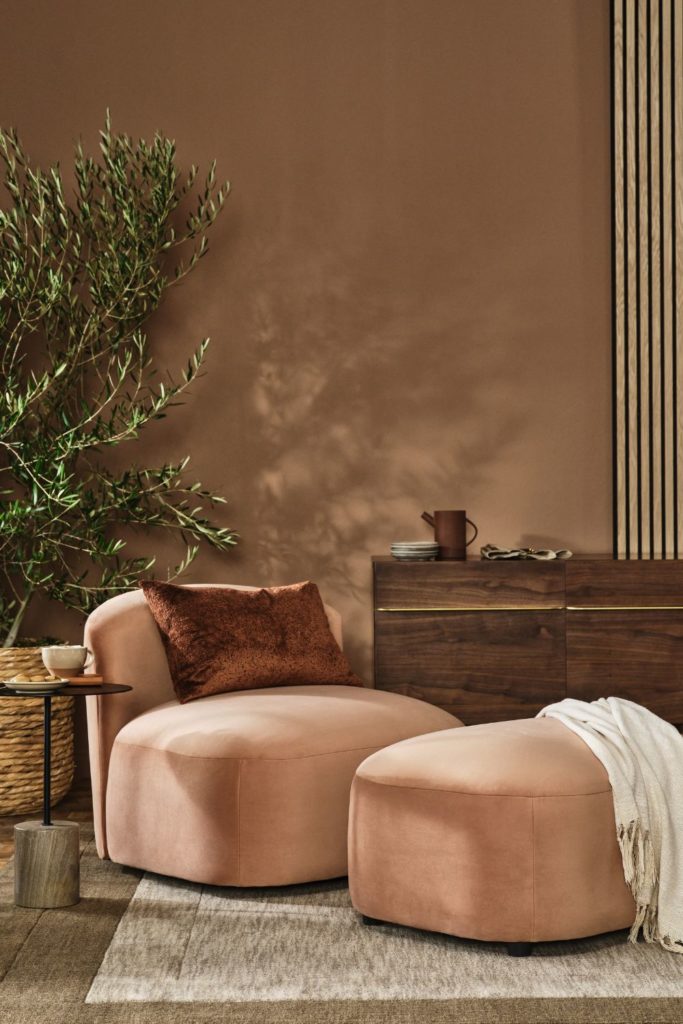 Pale brown sofa with dark brown cushion, cream throw and mocha-coloured walls
