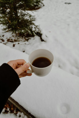 Hand holding mug in the snow