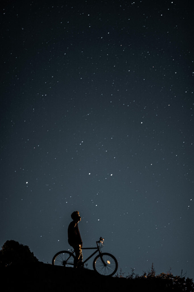 A man on a bike looking at a starry sky