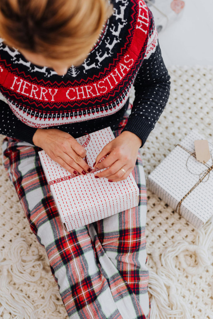 A woman wrapping a gift in a Christmas jumper