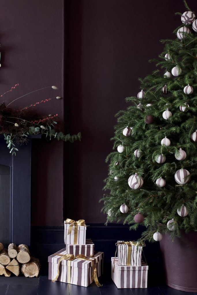 Christmas tree with gold and white baubles, against a dark purple wall