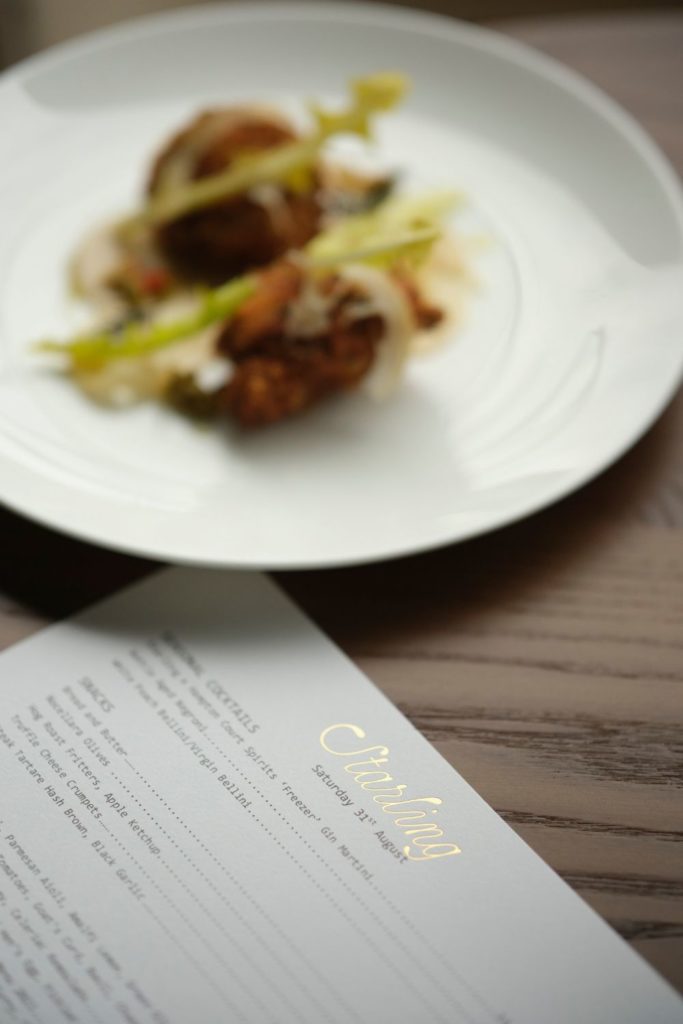 Starling menu beside a plate of duck and vegetables