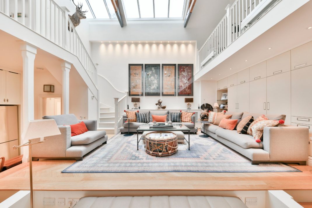 Studio living room with grey sofas, orange cushions and a skylight above