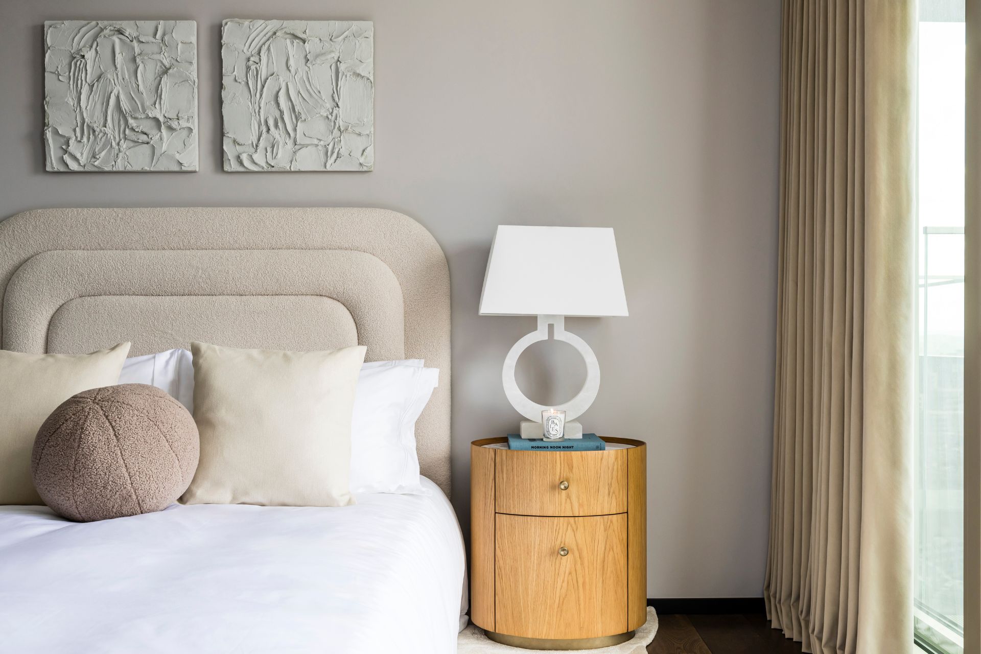 Bedroom with curved cream boucle headboard and cylindrical oak bedside table