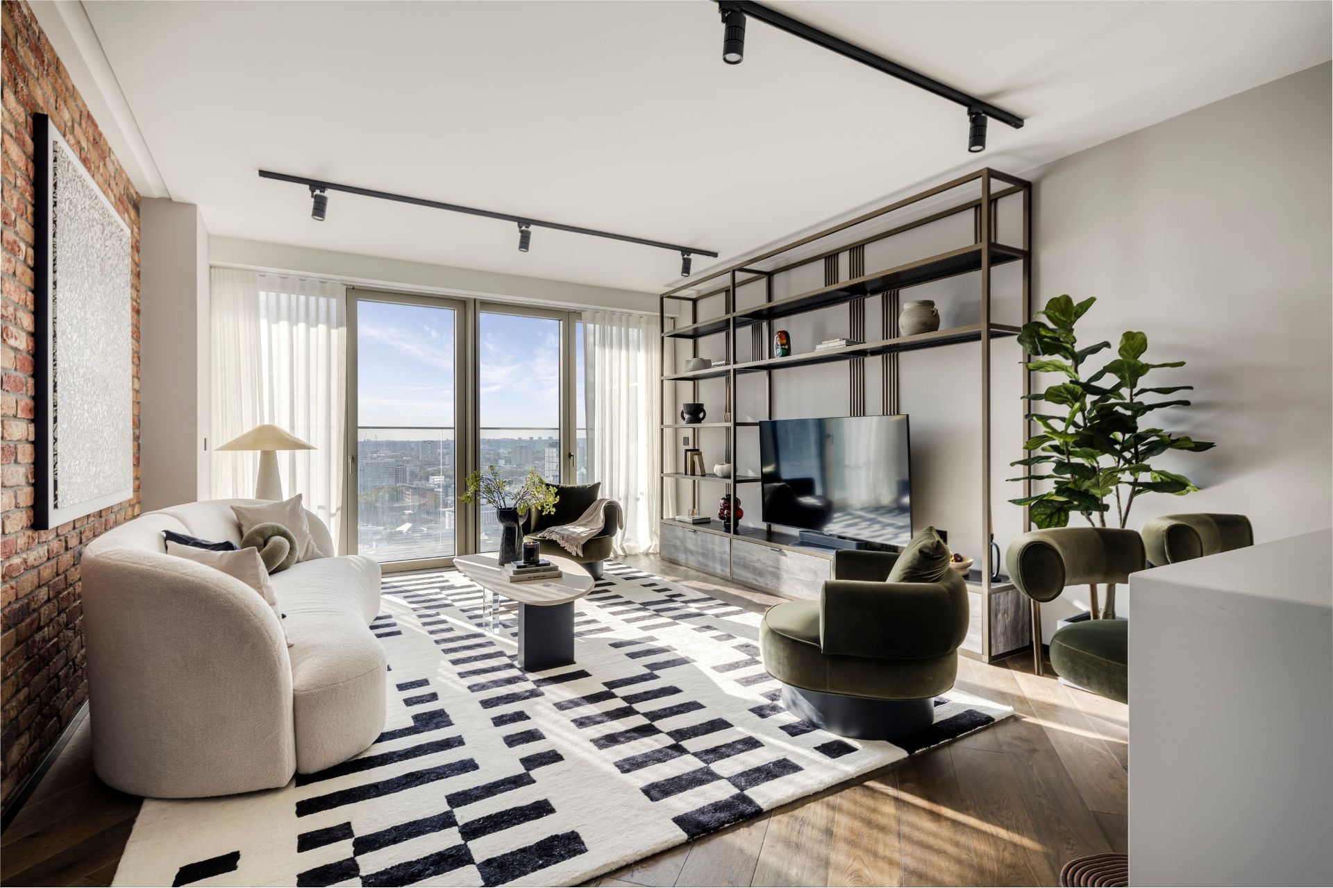 Living room with cream curved sofas, green velvet chairs and open shelving