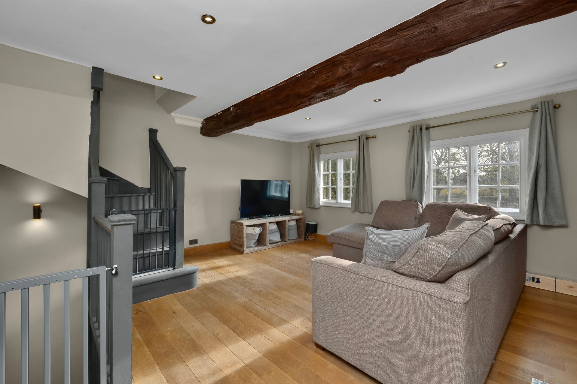 Living room with ceiling beams, wooden floors and beige sofas