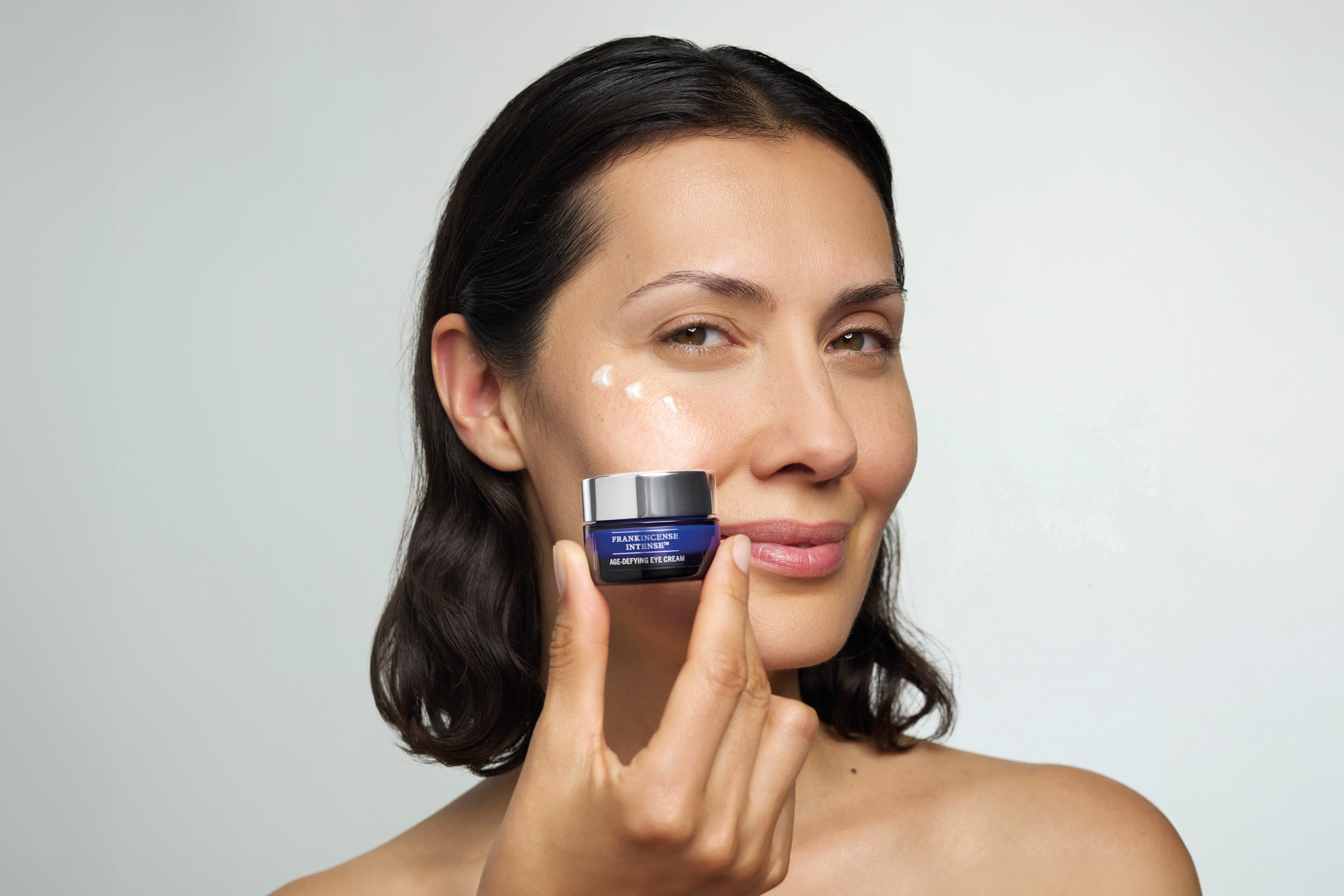 A woman holding a beauty product to her face
