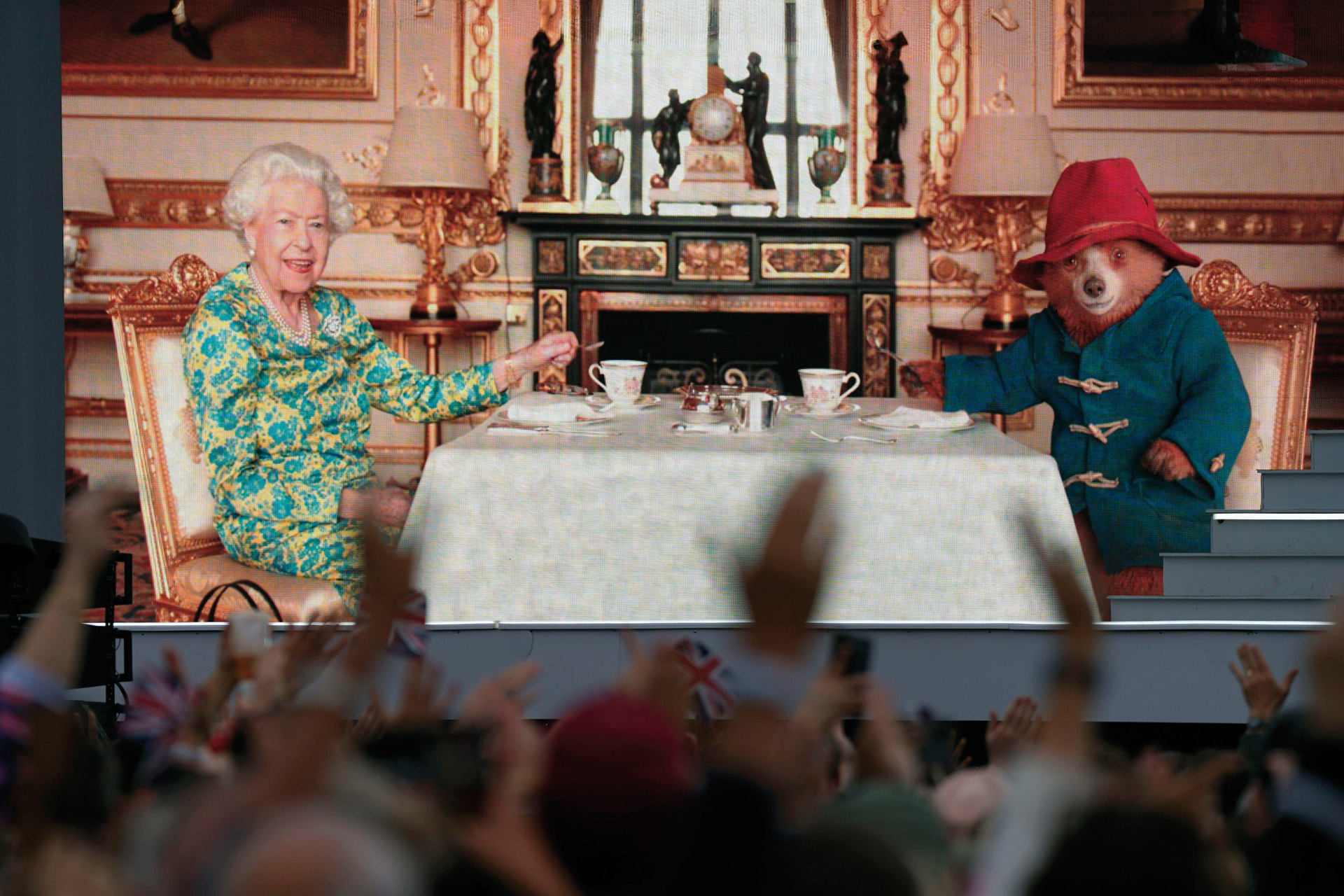 A crowd watching a film of Queen Elizabeth II having tea with Paddington Bear on a big screen during the Platinum Party at the Palace staged in front of Buckingham Palace, London on day three of the Platinum Jubilee celebrations for Queen Elizabeth II