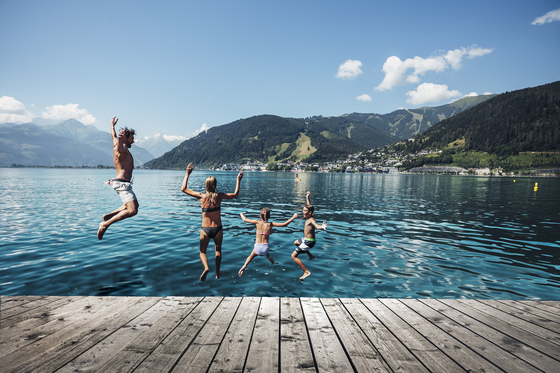 A family jumping into a lake during summer