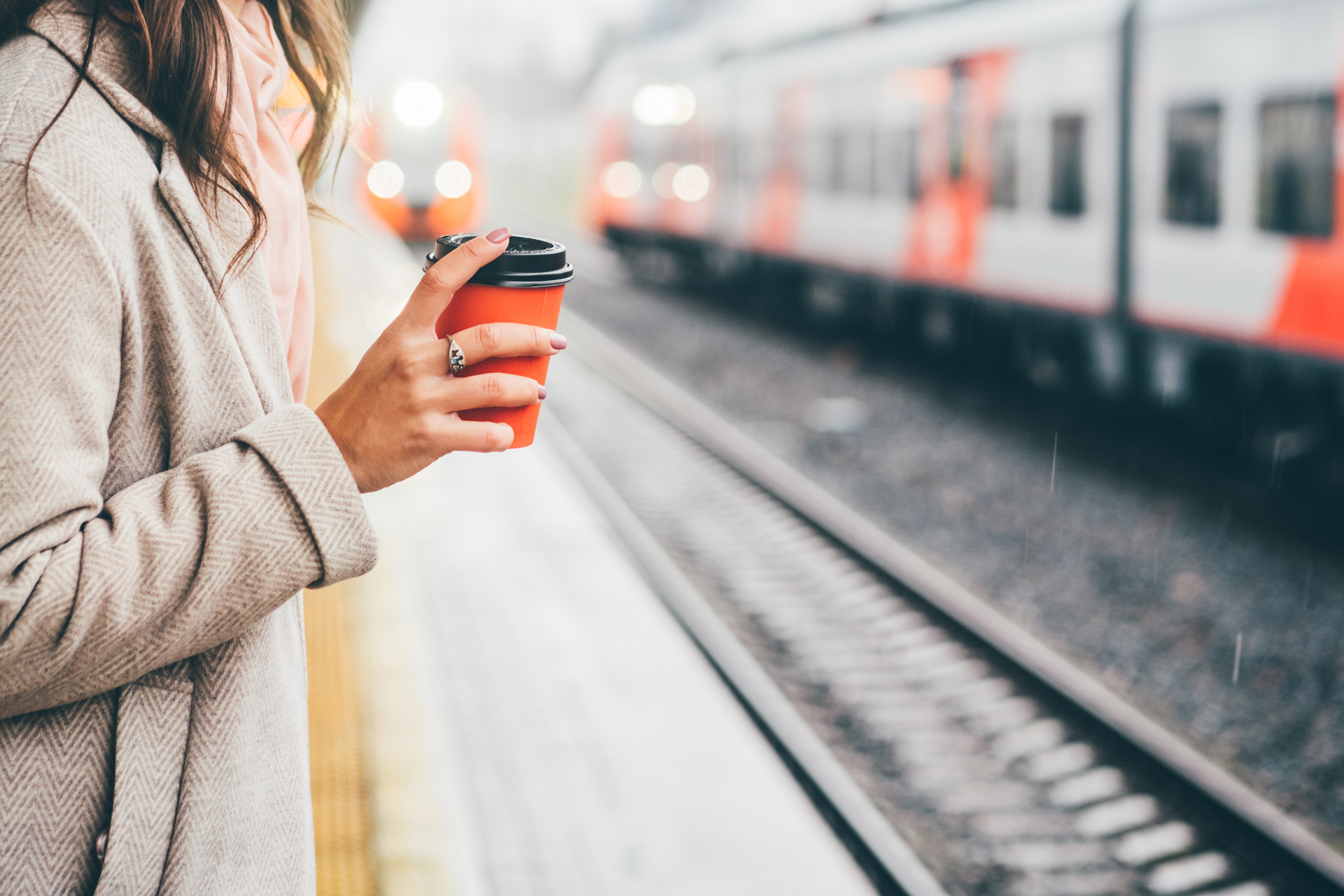 Woman with coffee at a train station