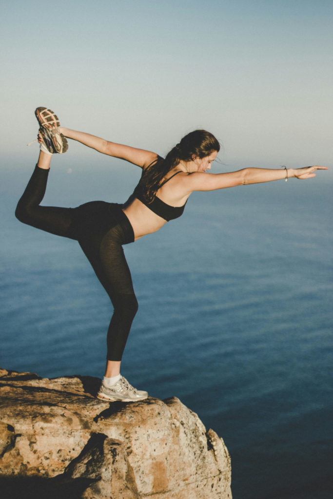 Woman stretching by ocean | fitness new year resolution