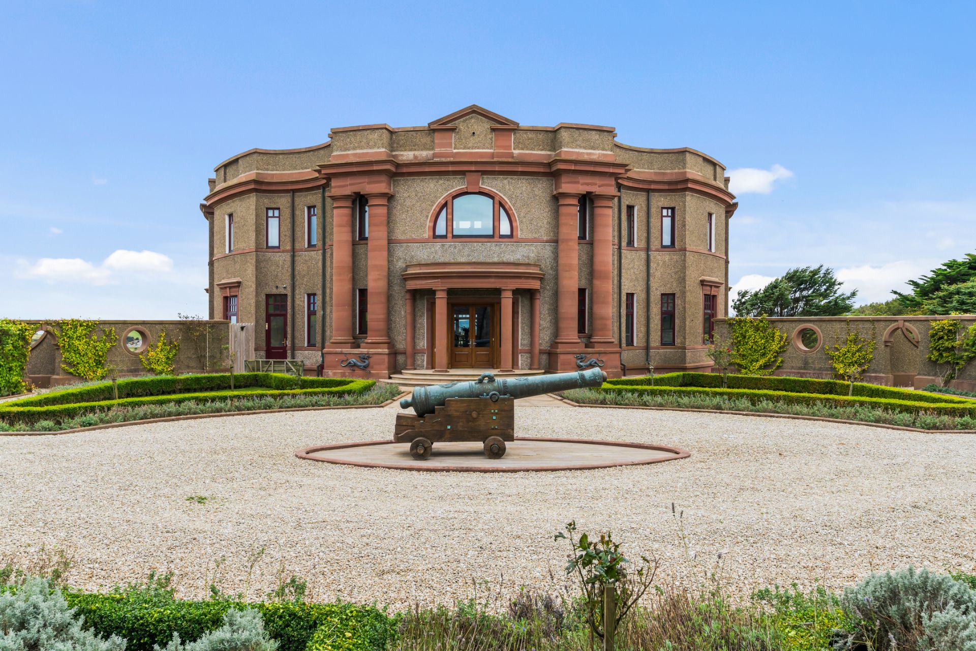 Palladian building with a cannon in the centre of the gravel driveway