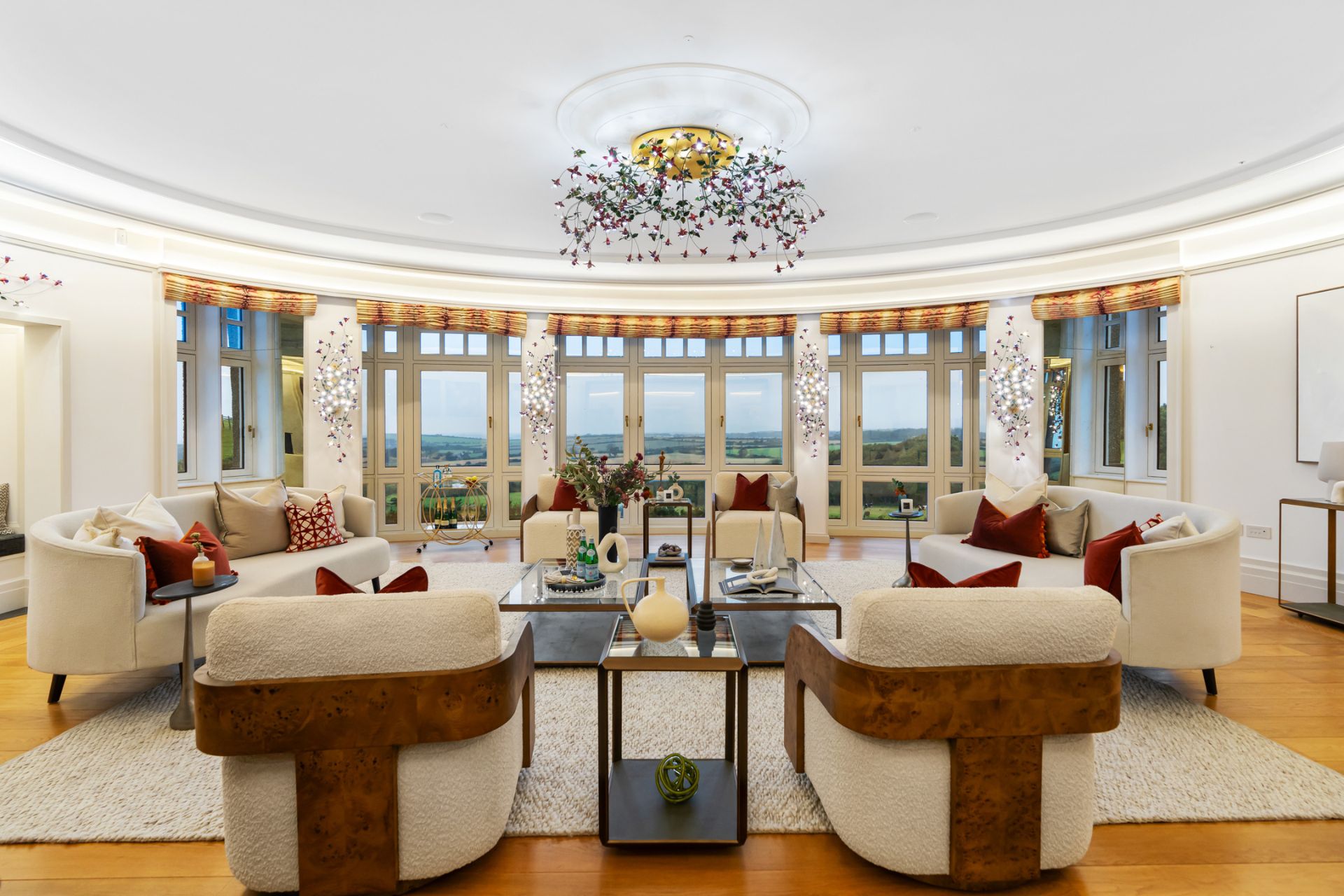 Elliptical living room with cream sofas, orange cushions and black console tables