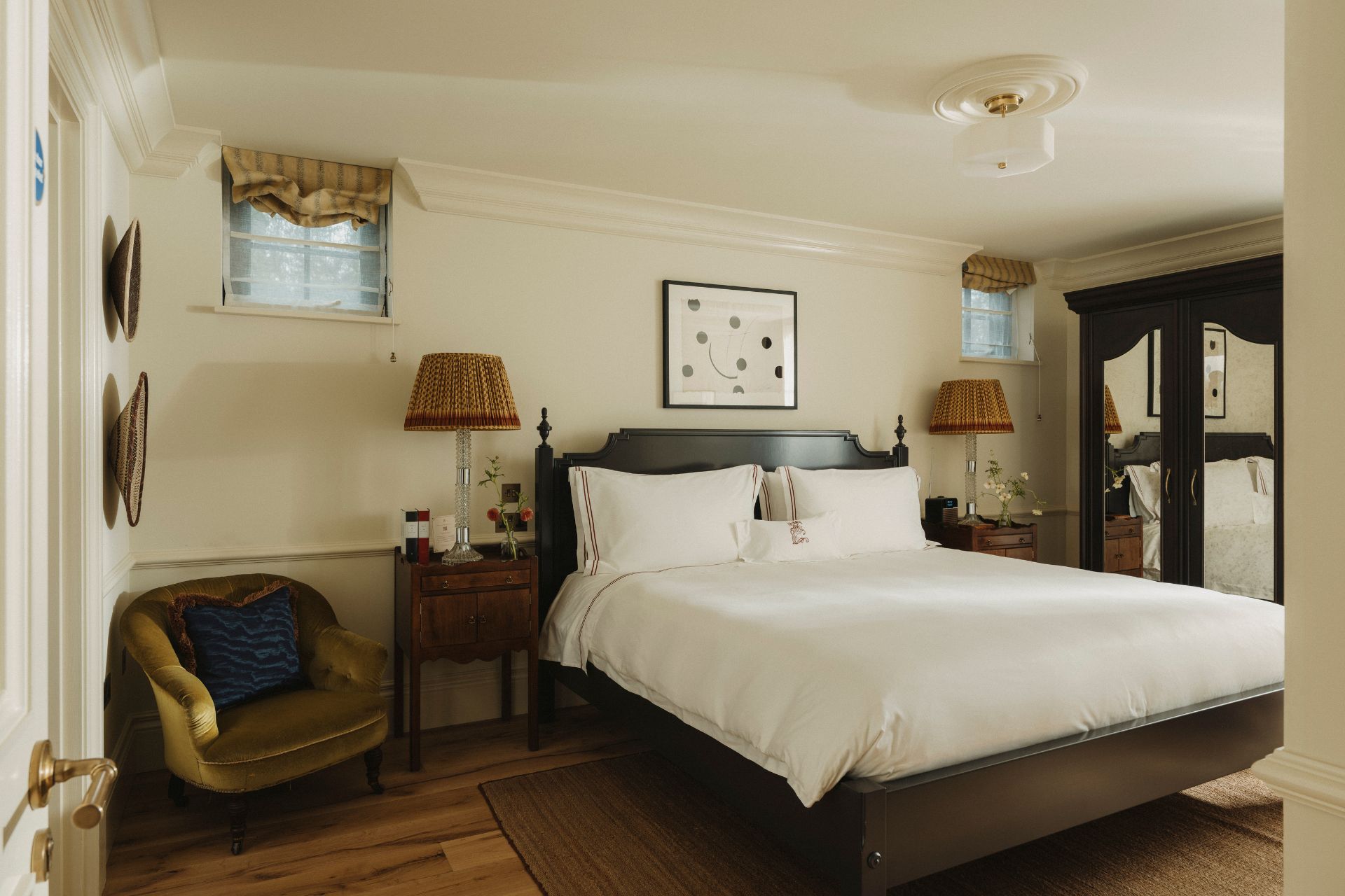 Estelle Manor lodge bedroom with white sheets, red lamps and a mahogany bed