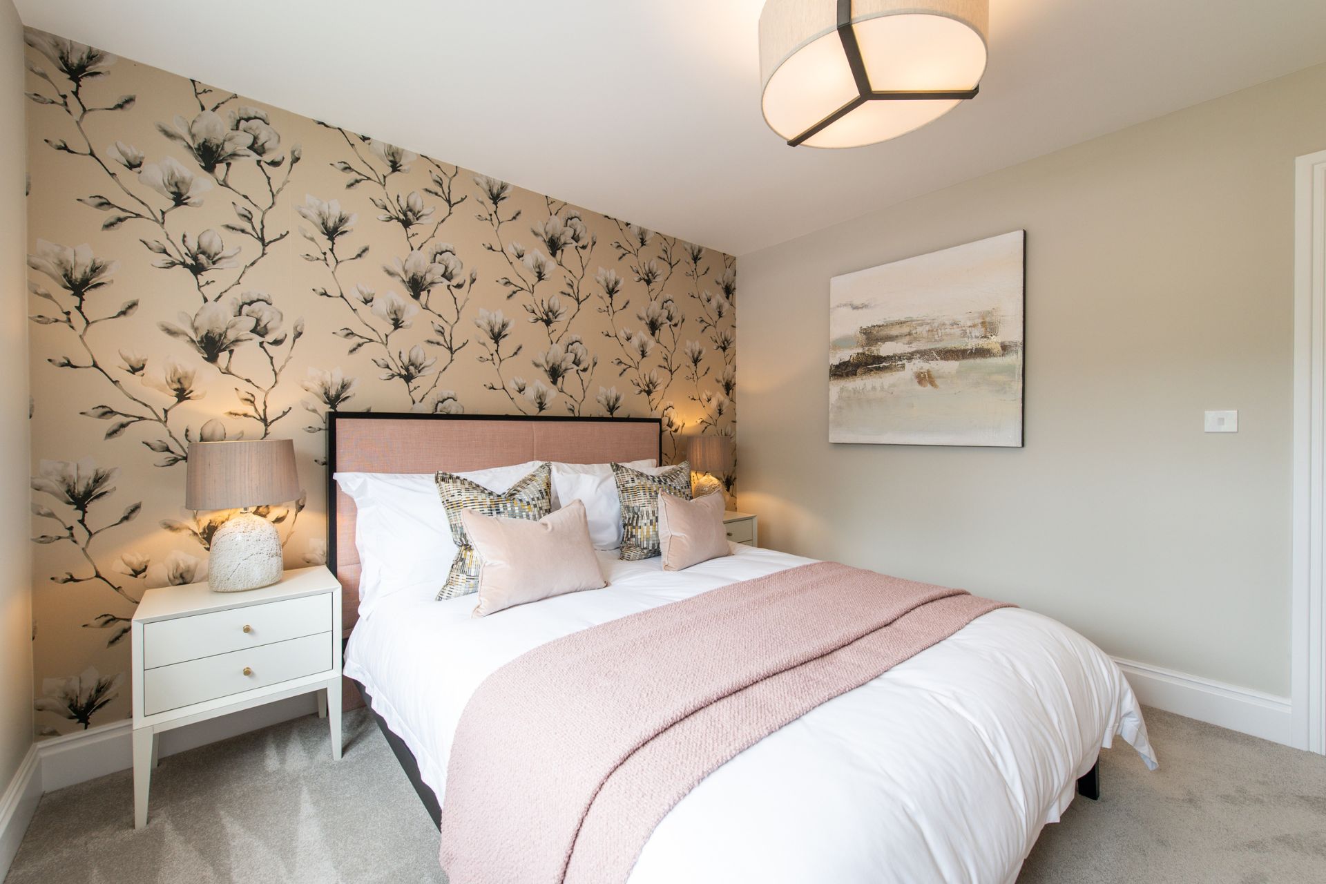 Bedroom with taupe floral wallpaper, white bedsheets and a pink bedspread.