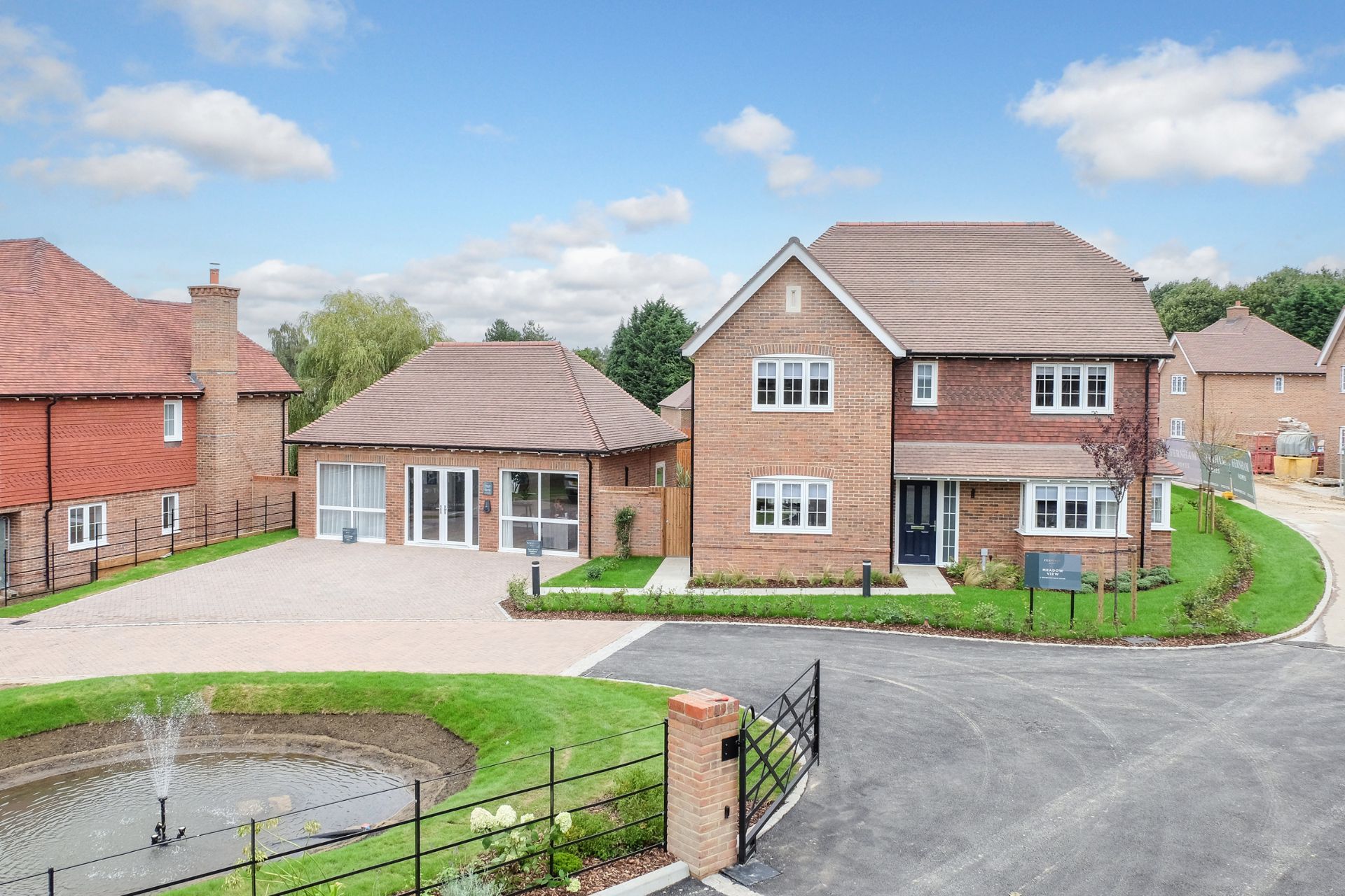 Red brick Kent homes with large driveways and a central pond with a fountain