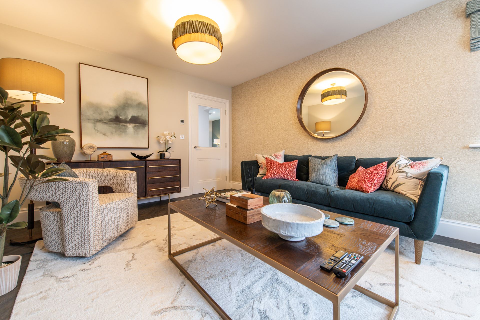 Living room with a cream and grey patterned rug, navy velvet sofa, cream Art Deco chair and bronze coffe table.