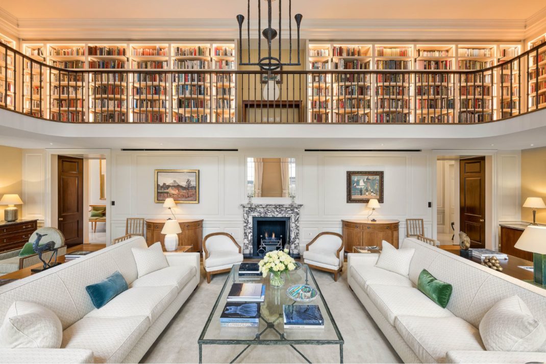 Living room with cream sofas and a mezzanine level lined with bookshelves