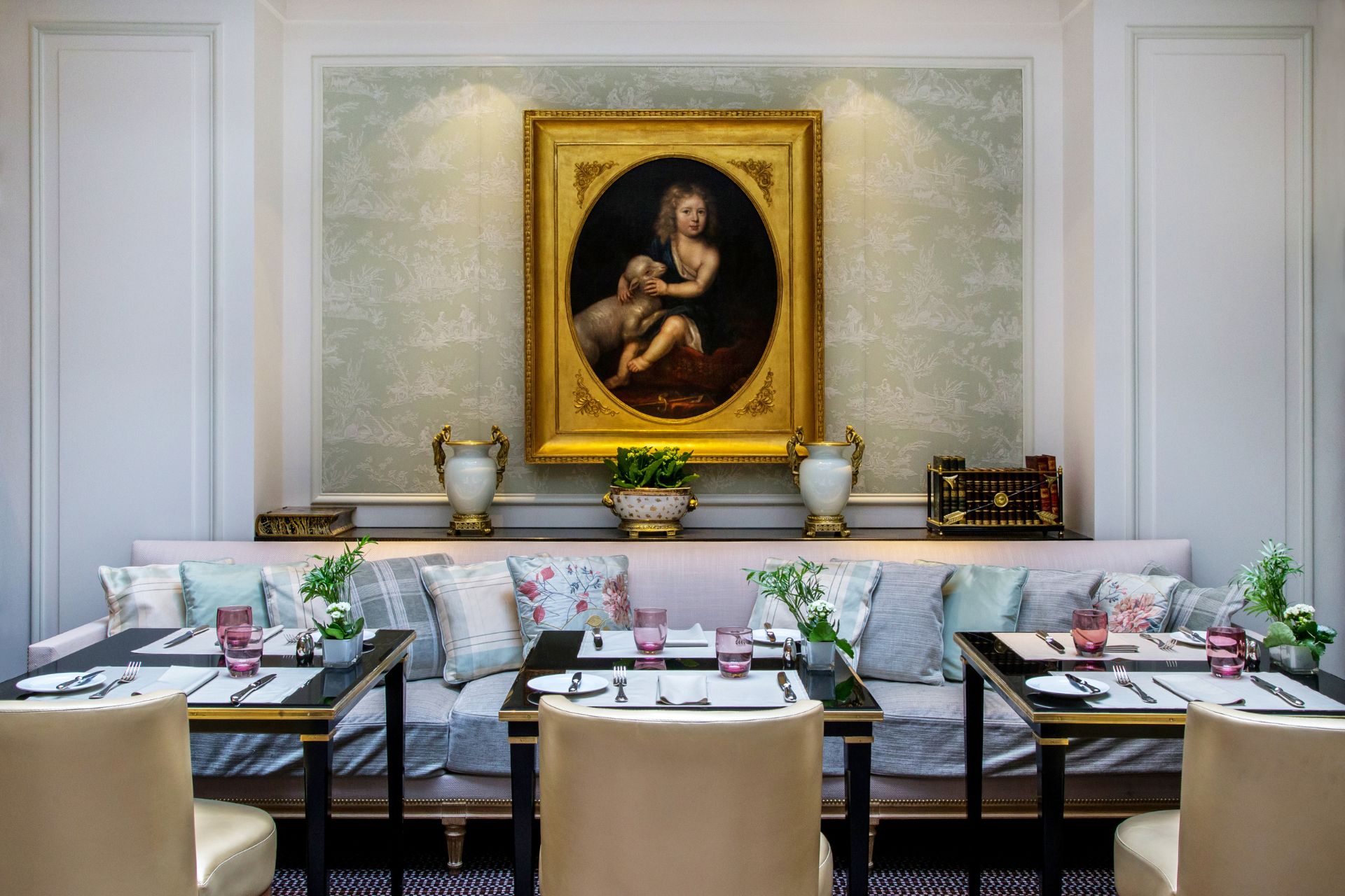 Dining room with gold picture frames, floral wallpaper and pale blue banquettes