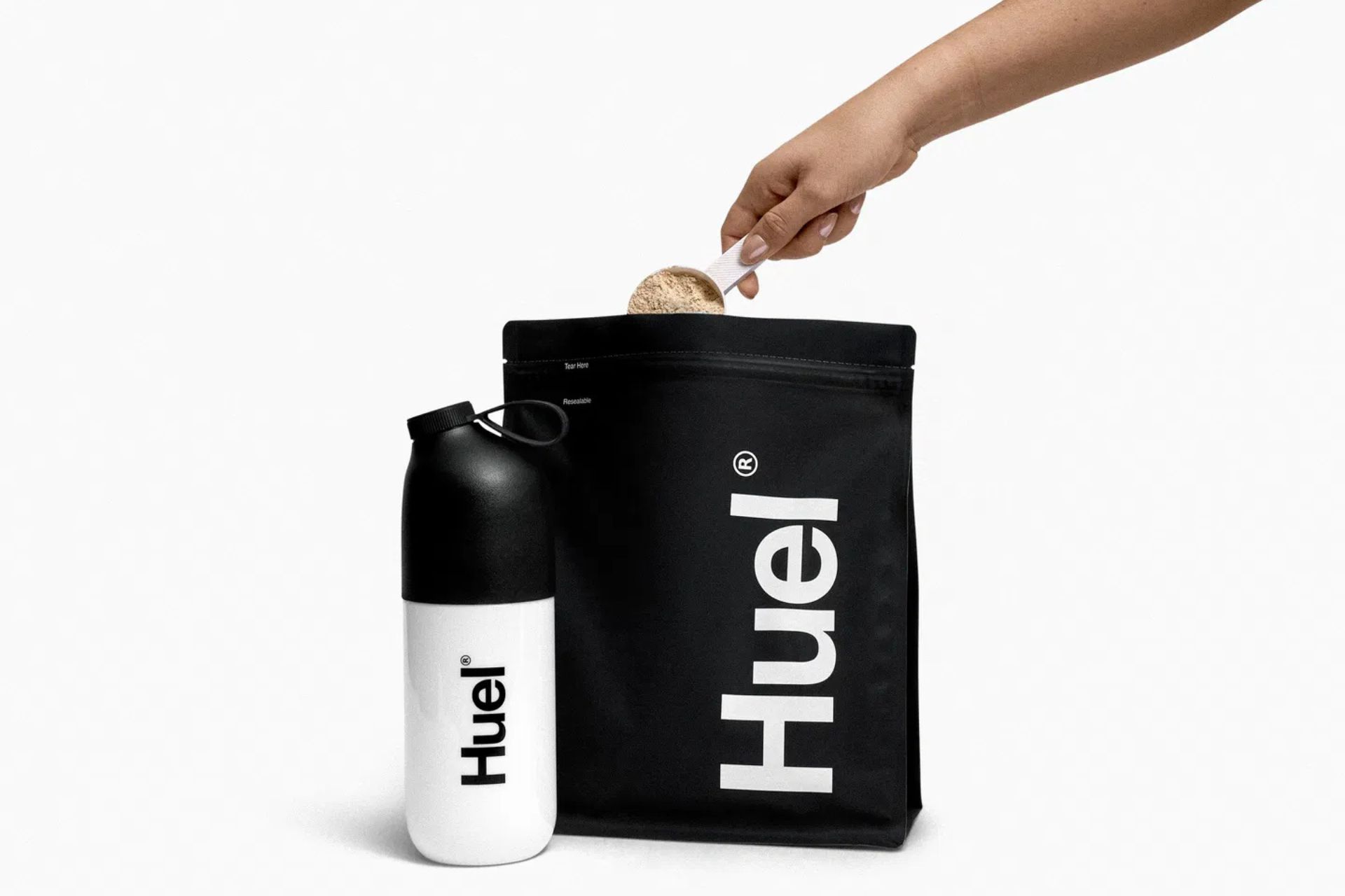 Black pouch of protein powder with Huel branded bottle