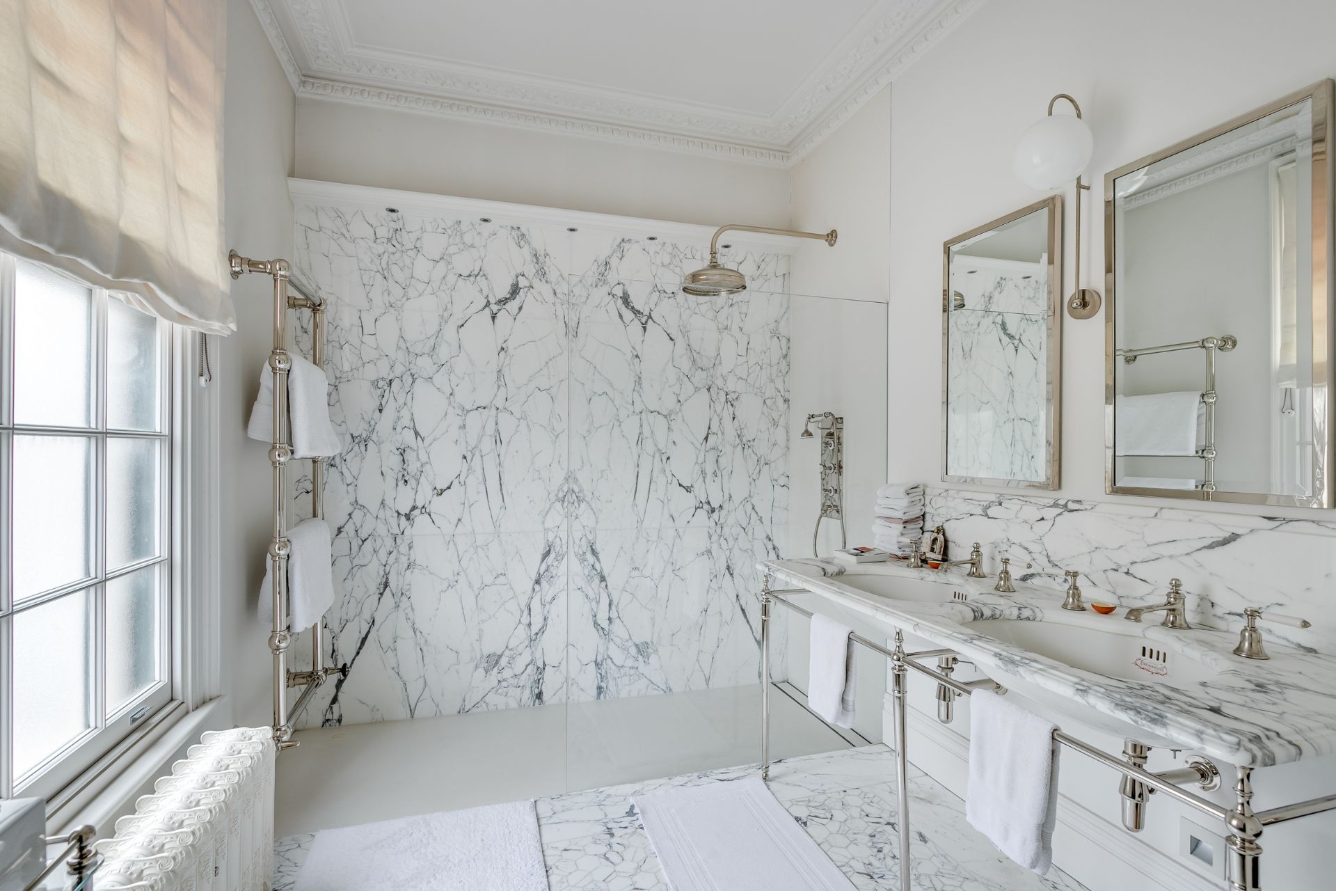 Marble-clad bathroom with double vanity and walk-in shower