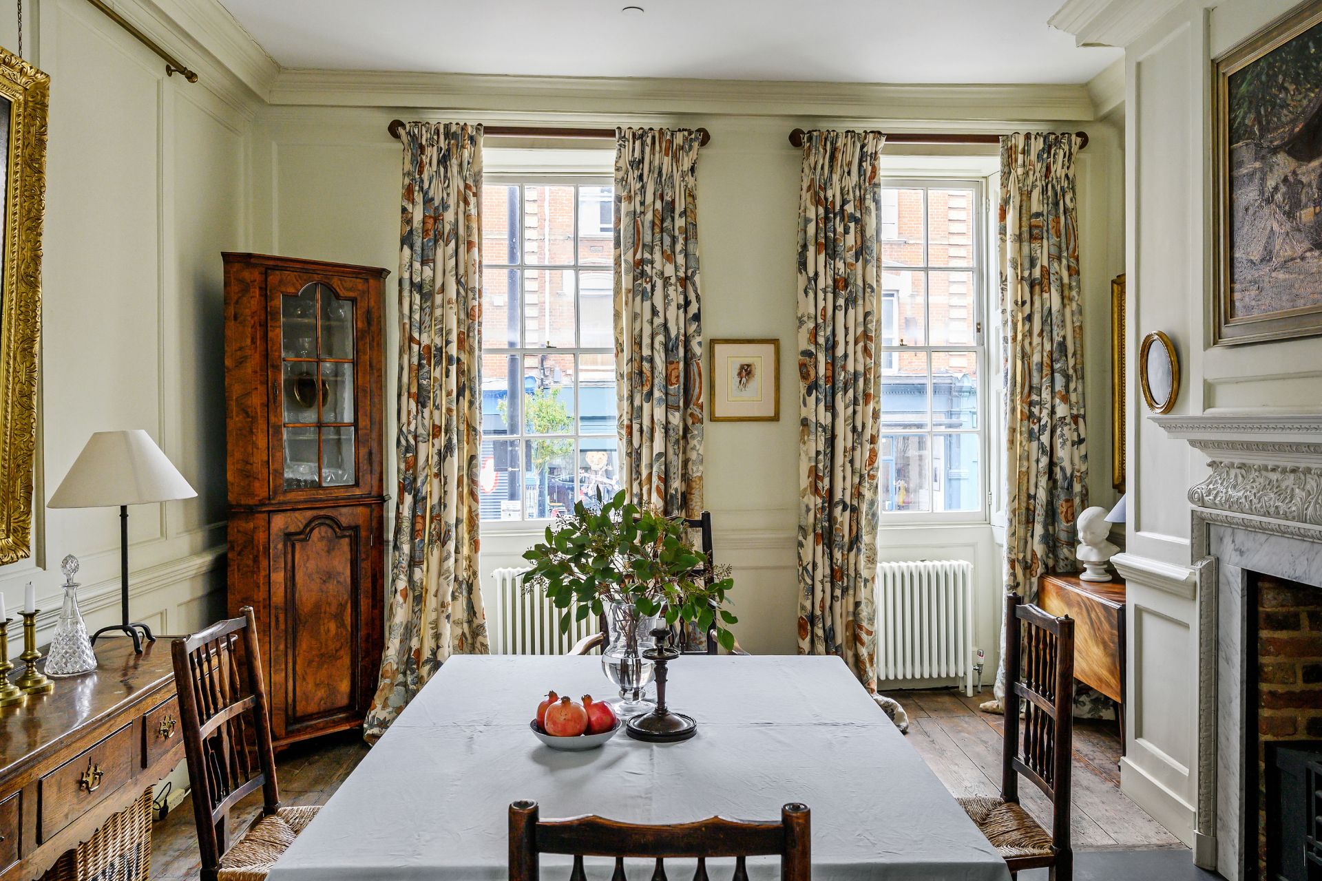 Dining room with floral curtains and a wooden dresser.