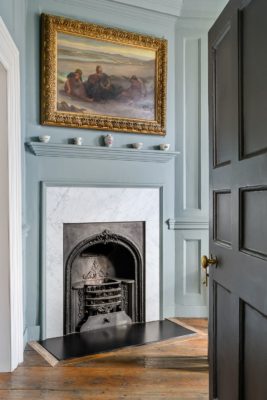 Living room with powder blue walls and a fireplace with a marble surround