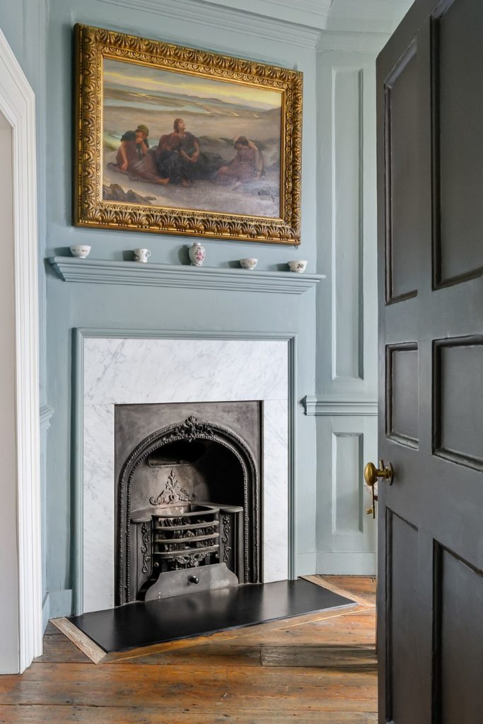 Living room with powder blue walls and a fireplace with a marble surround