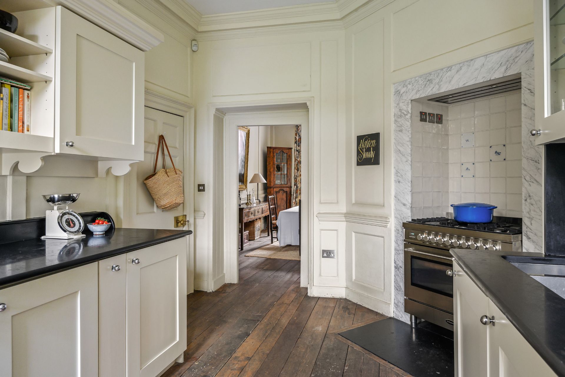 Kitchen with white cabinets, black slat worktps and wood floors.