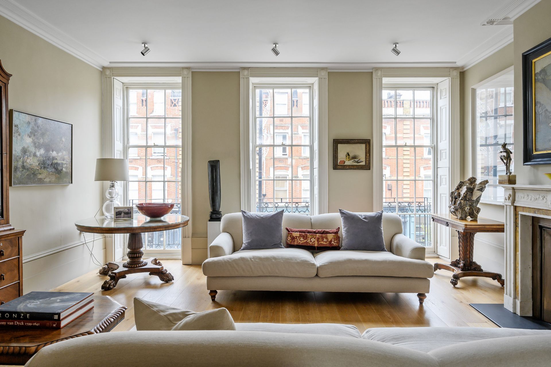 Living room with wood floors, sash windows and cream sofa.
