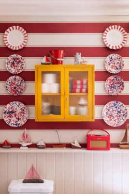 Red and white striped bathroom with yellow wall cabinet and nautical decor