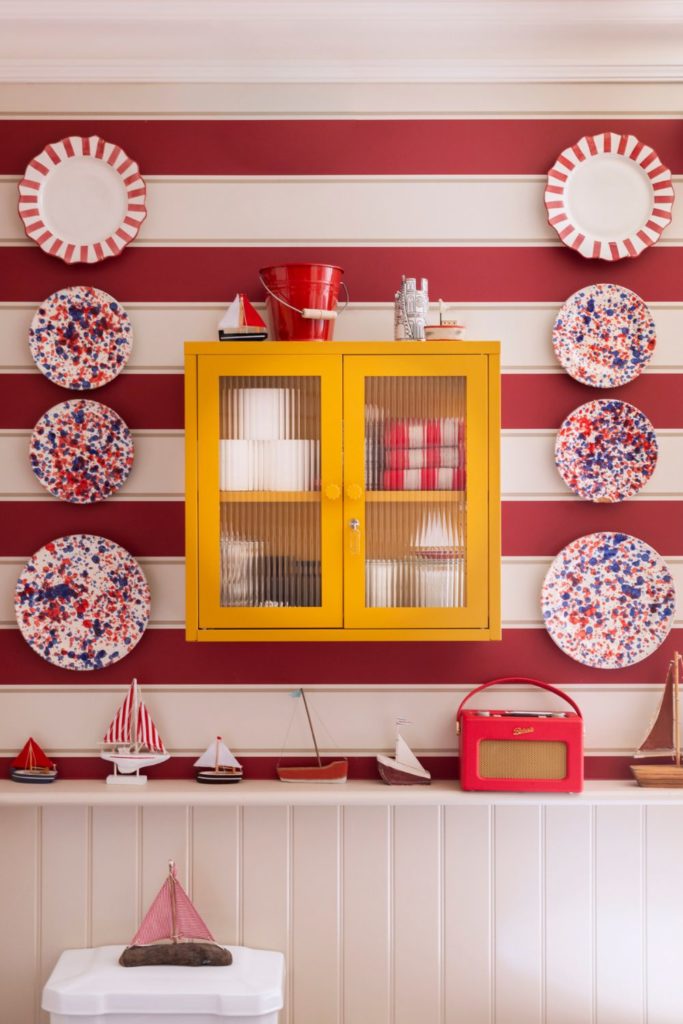 Red and white striped bathroom with yellow wall cabinet and nautical decor