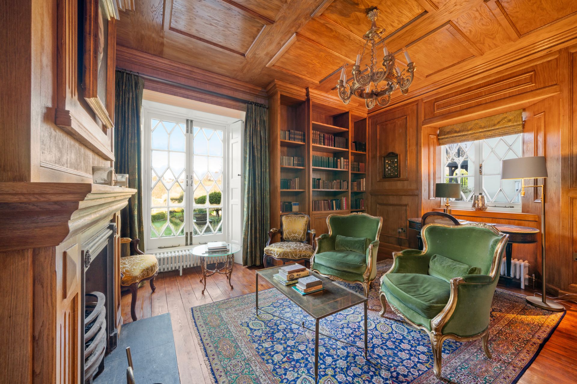 Oak-panelled library with green velvet chairs