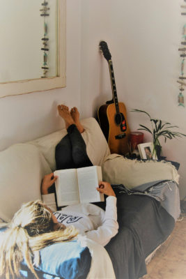 A woman reading a book on a sofa