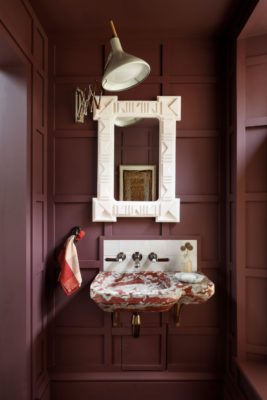 Colour-drenched burgundy powder room with a white mirror and a red and white marble sink unit