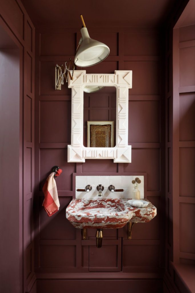 Colour-drenched burgundy powder room with a white mirror and a red and white marble sink unit