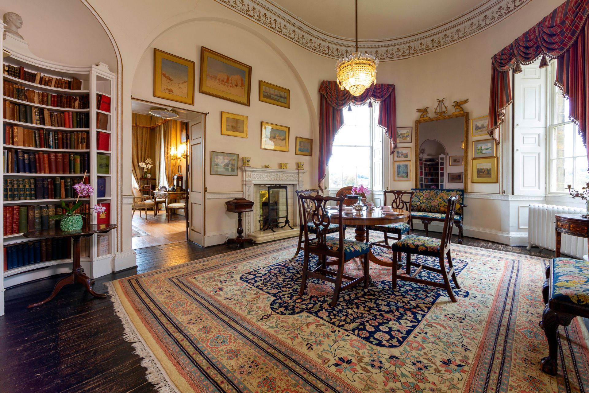 Castle library with red velvet curtains, mahogany furniture and a chandelier