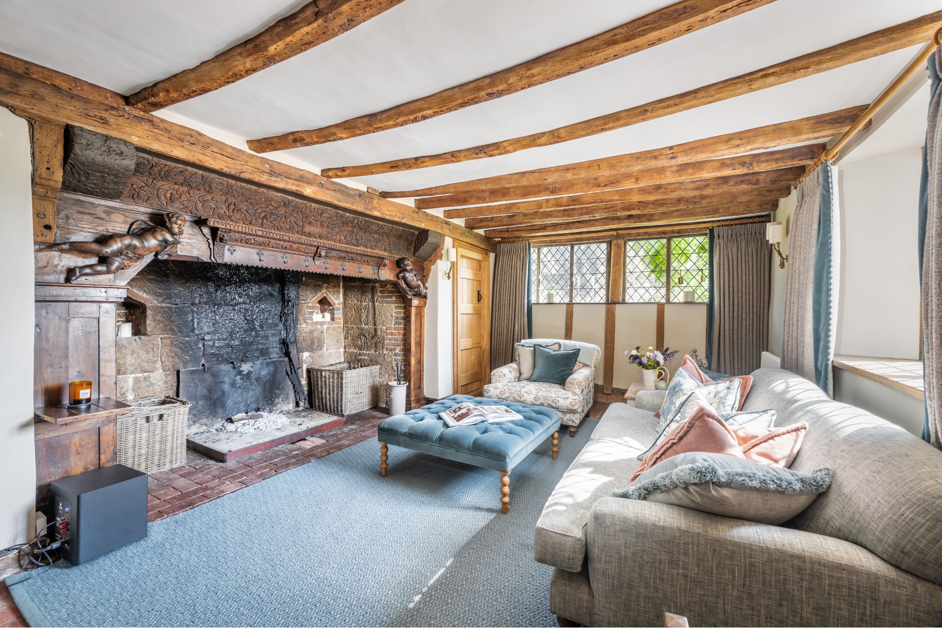 Living room with wooden ceiling beams, an inglenook fireplace and a cream sofa