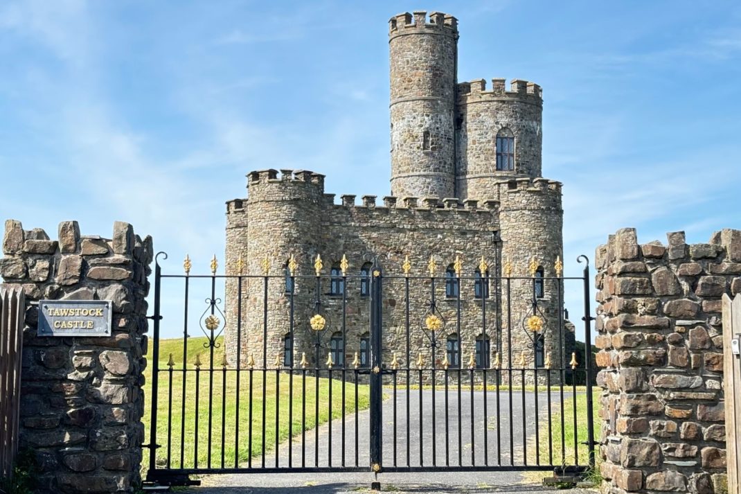 Exterior of Bailey castle in Devon, with wrought iron gates and a long driveway