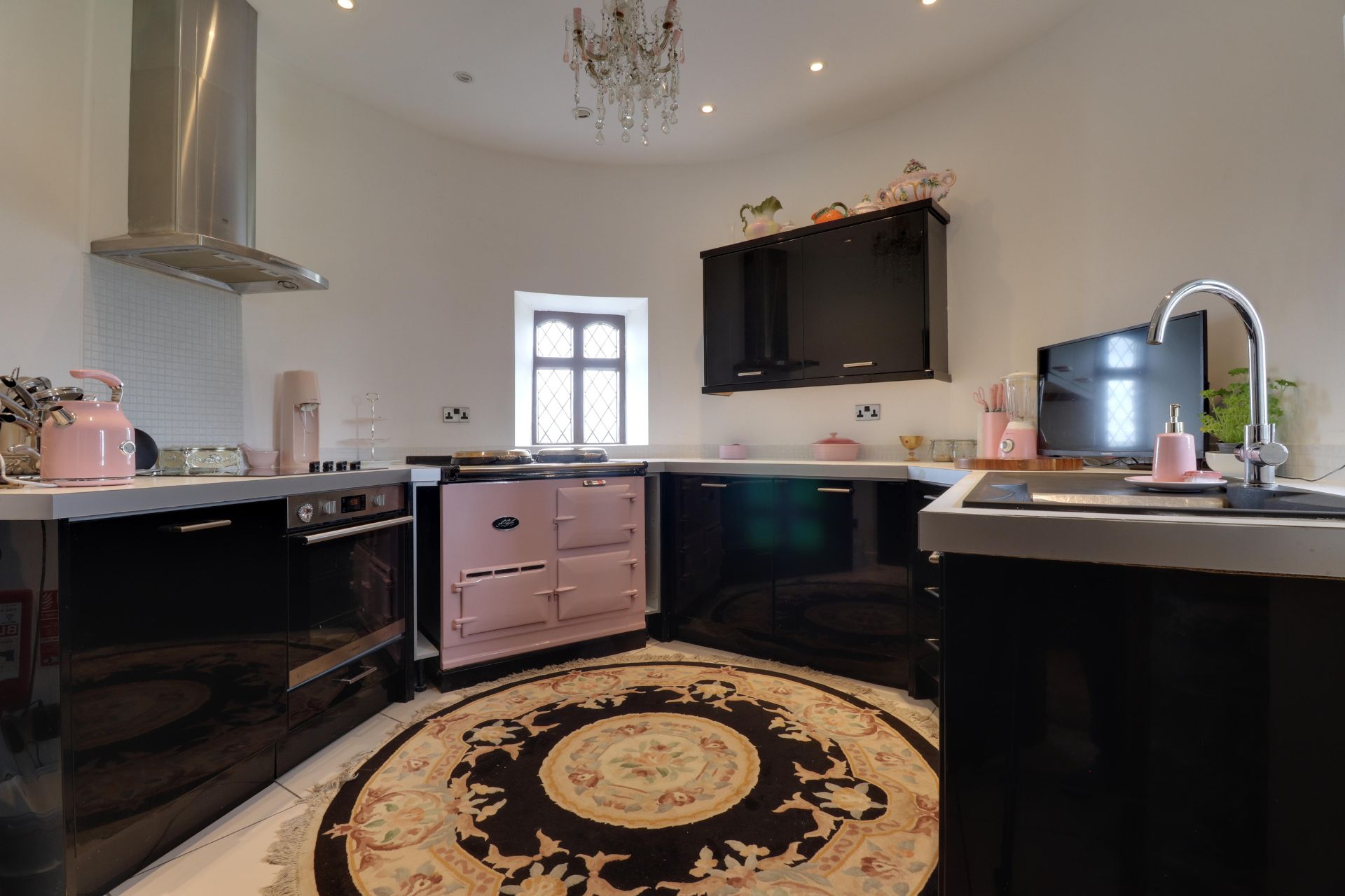 Circular kitchen with black cabinets and a pale pink AGA