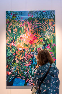 A woman admiring a painting at Affordable Art Fair